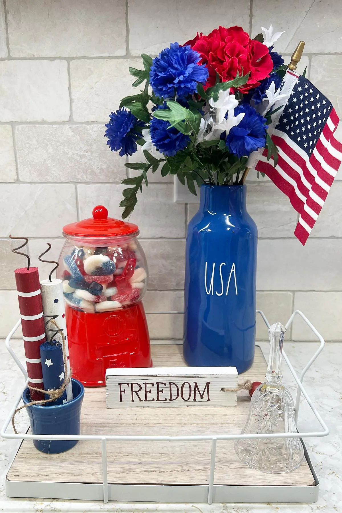 A 4th of July themed decor with a blue vase of flowers, red gumball machine, and a