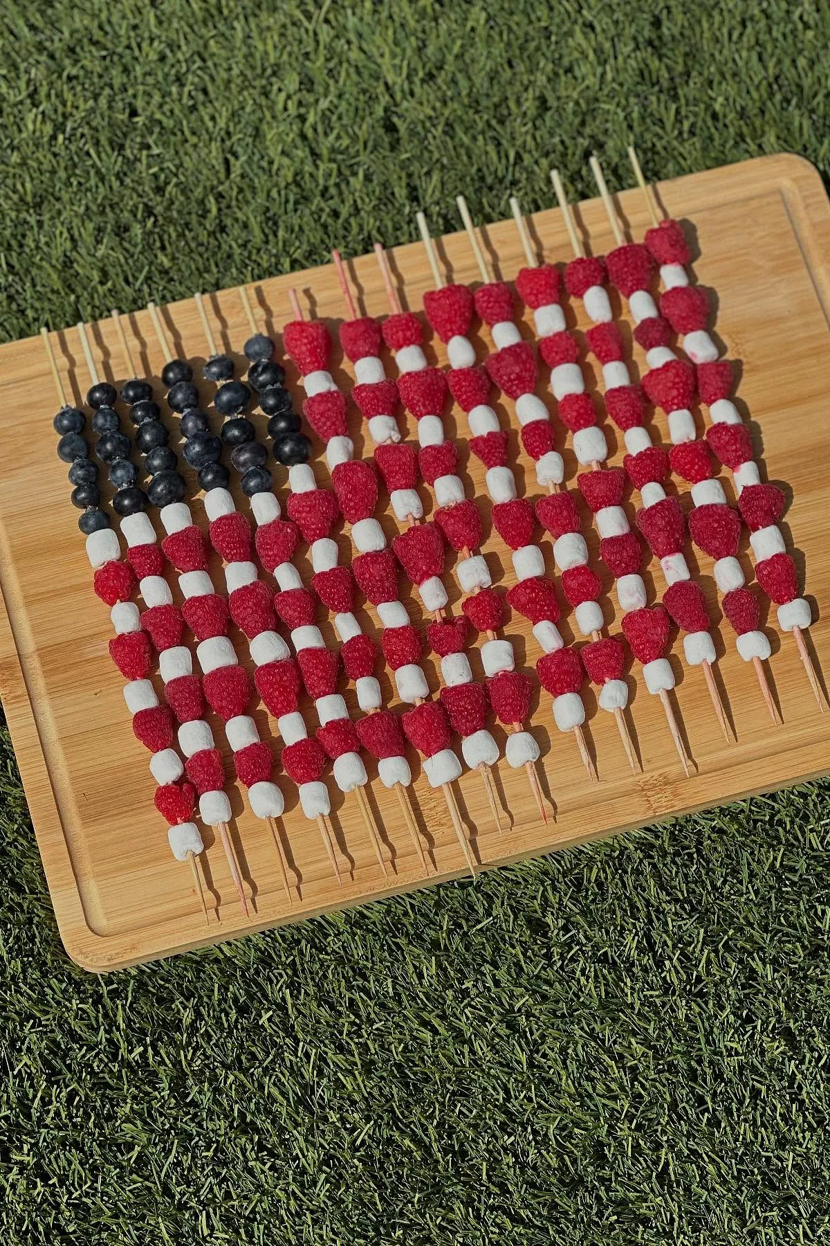 4th of July fruit kabobs arranged like an American flag with raspberries, marshmallows, and blueberries.