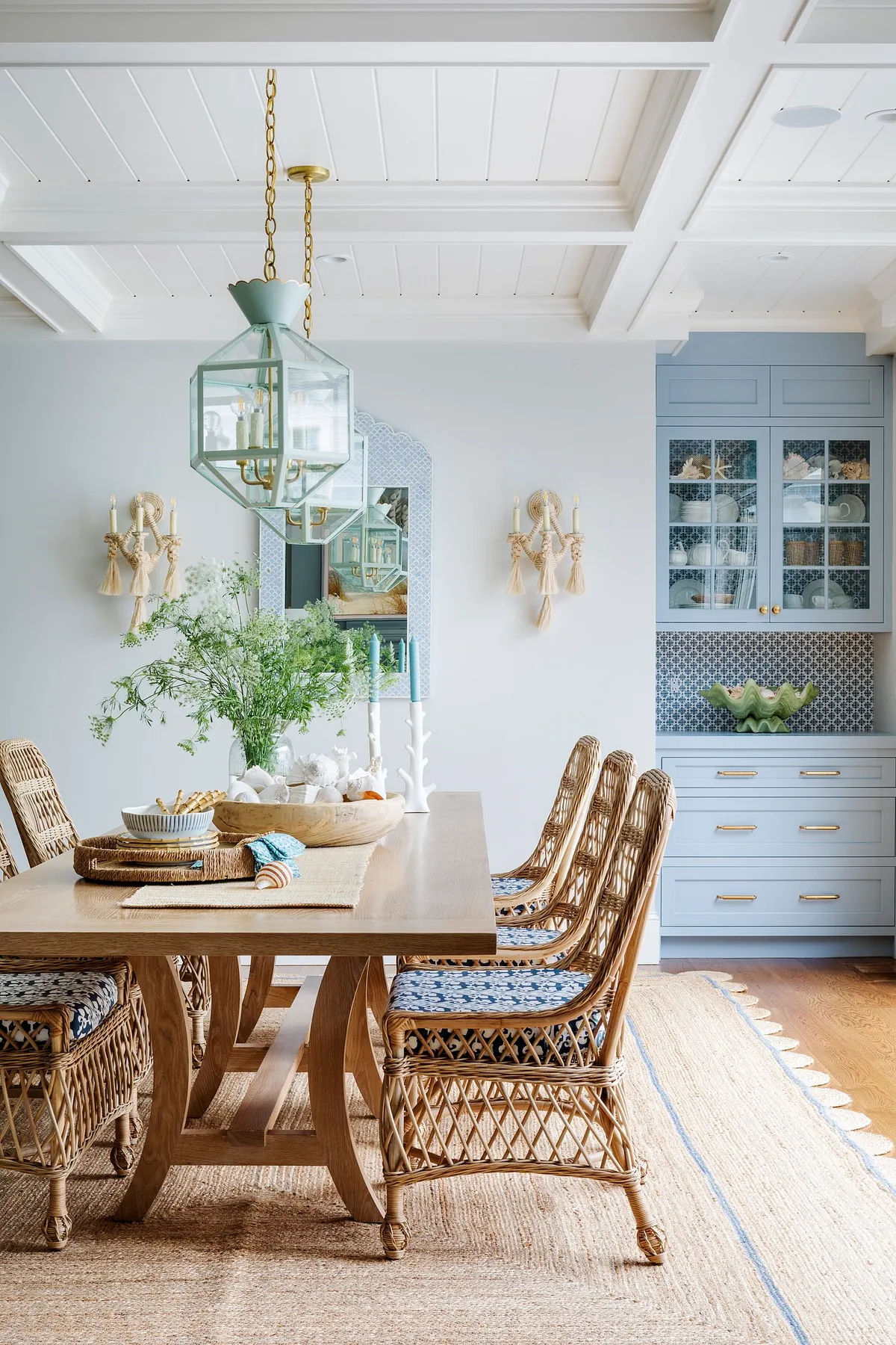 A coastal-inspired dining area featuring a wooden table, woven chairs, and floral centerpiece.