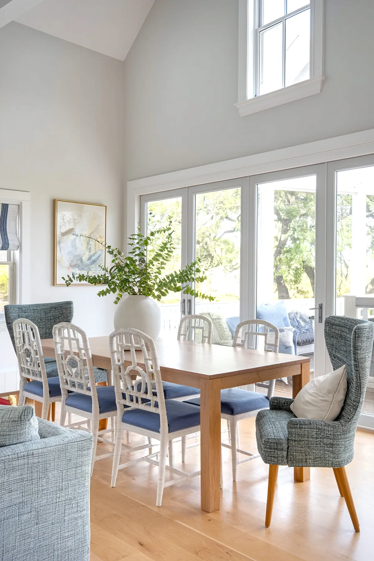 Bright dining area with wooden table, stylish chairs, and lush greenery.