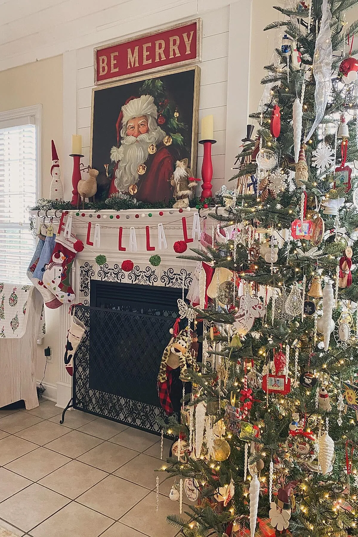 A traditional christmas tree decorated with long white icicle ornaments, red and gold baubles, Santa figurines, snowflakes, warm string lights with dense greenery in a cozy living room near a fireplace.