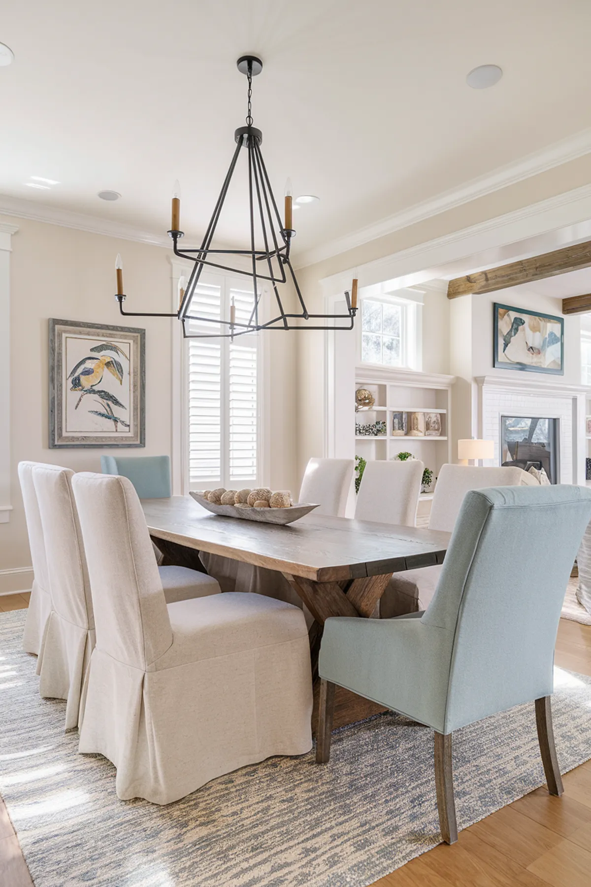Bright dining area featuring a wooden table, slipcovered chairs, and coastal decor.