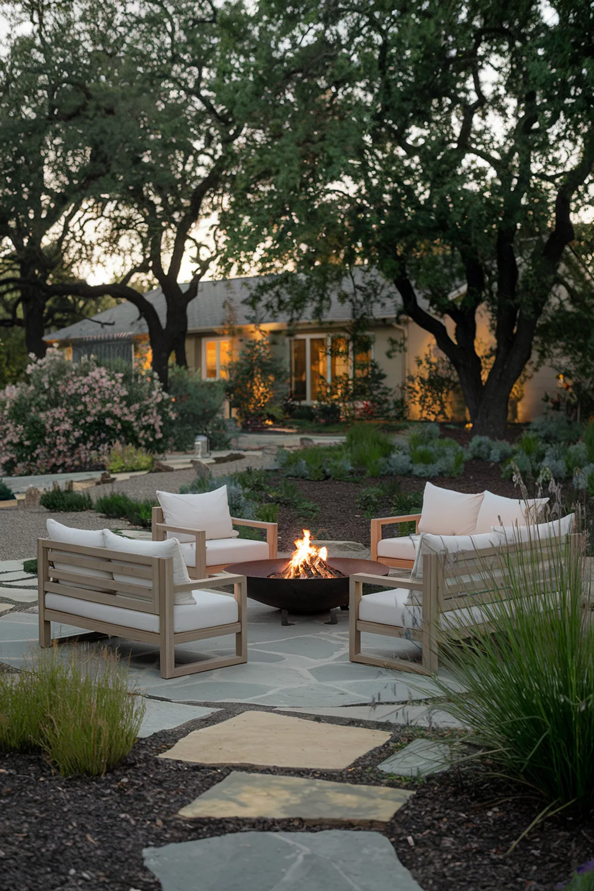 A modern backyard fire pit area with comfortable seating surrounded by lush greenery.