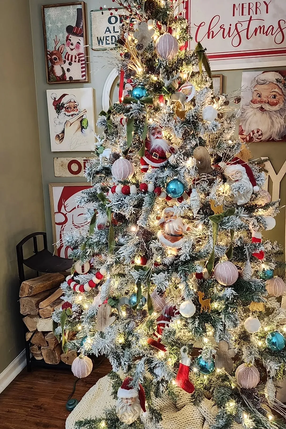 Flocked christmas tree decorated with red and white santa ornaments, blue glass baubles, and felt garlands in red and cream surrounded by framed vintage holiday art for a nostalgic vintage christmas aesthetic.