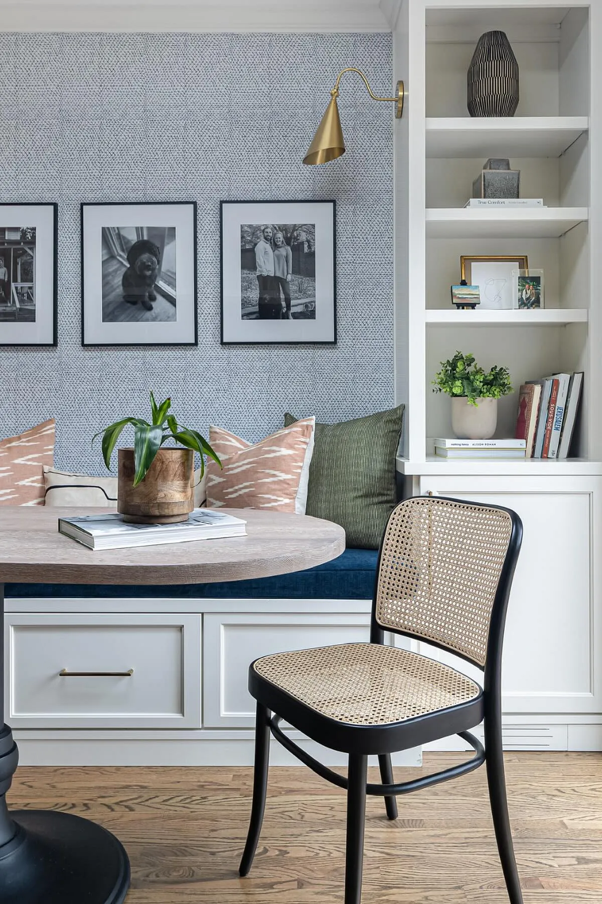 Cozy breakfast nook featuring a round table, plush pillows, wall art, and a stylish chair.
