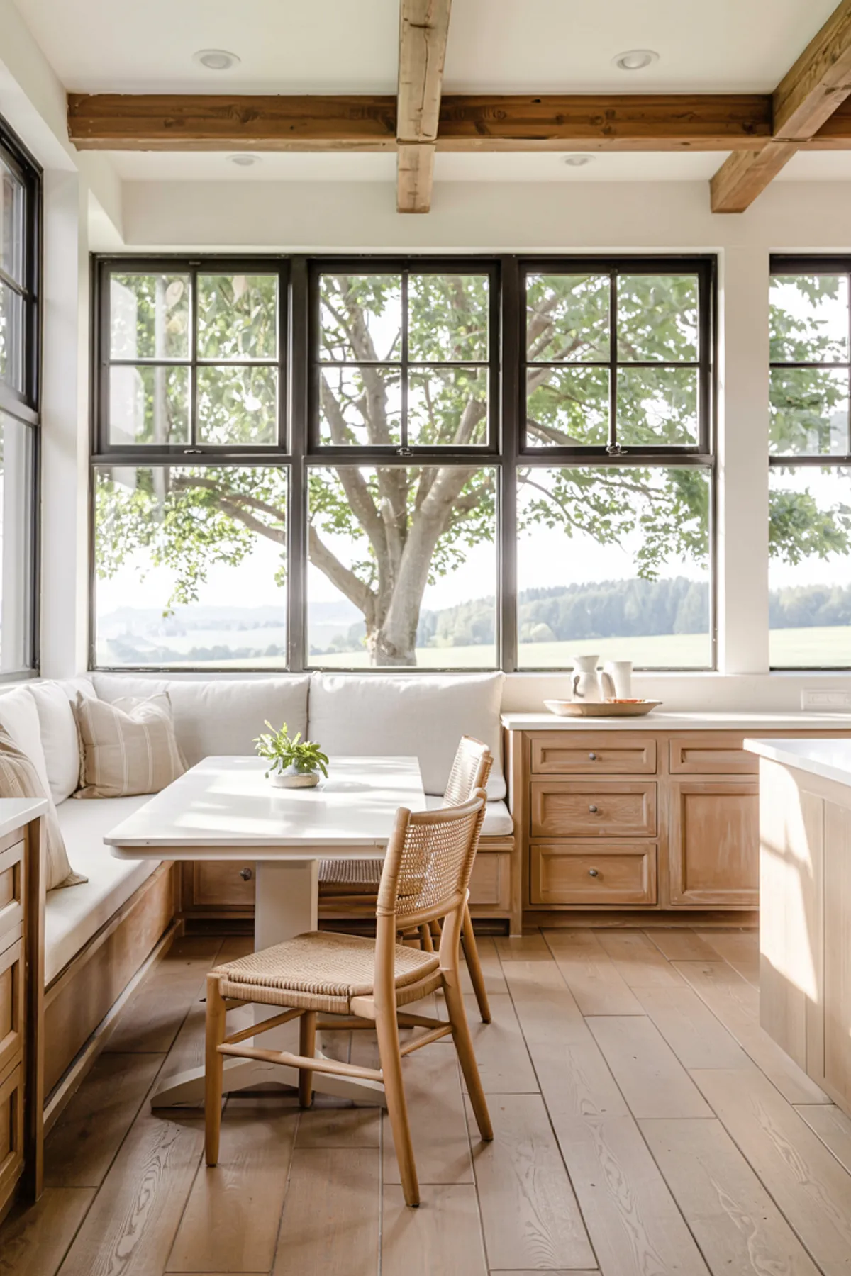 Bright breakfast nook featuring a cozy bench seating, wooden table, large windows with garden views.
