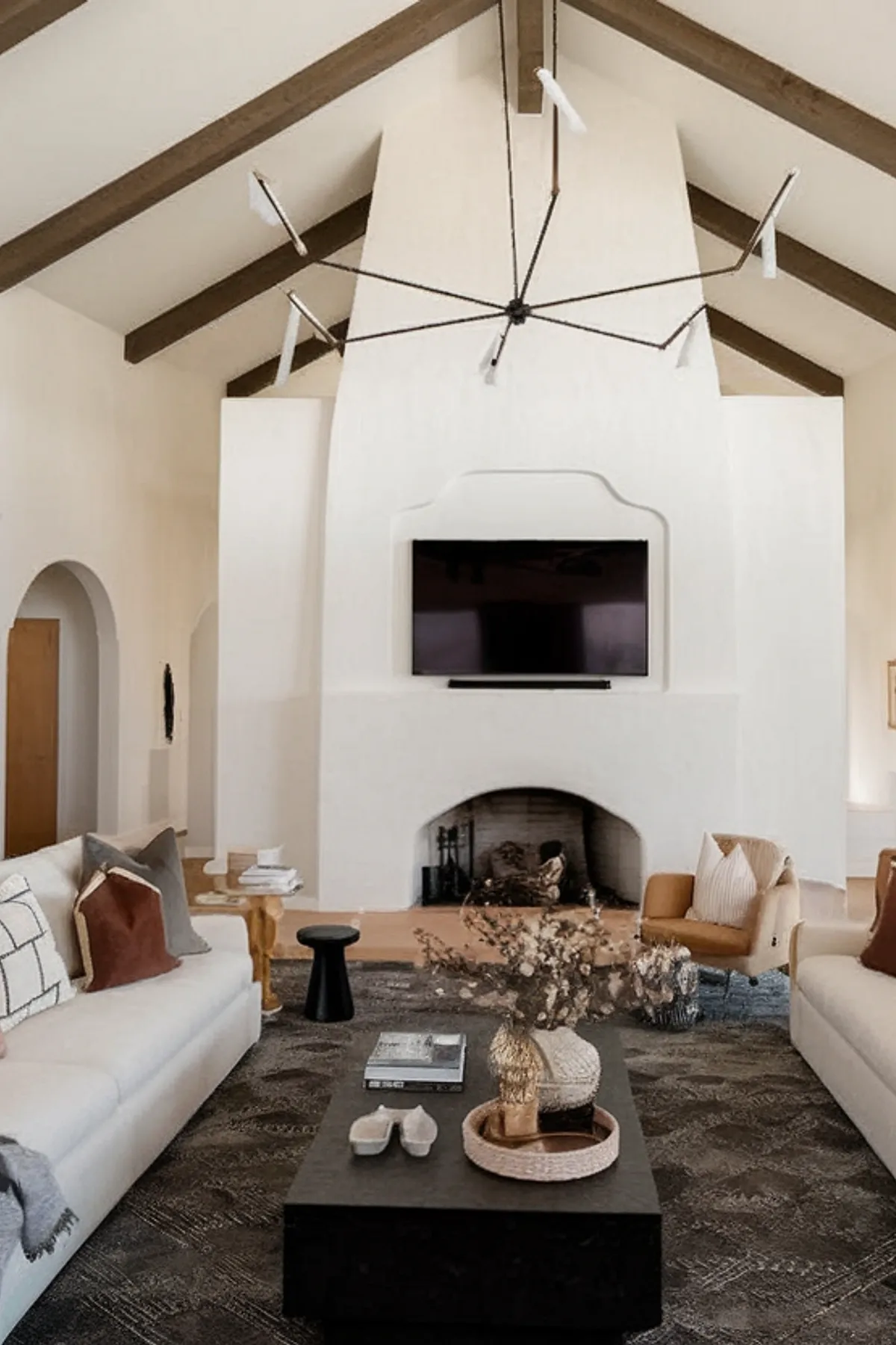 Modern living room featuring high ceilings, rustic beams, and stylish decor.