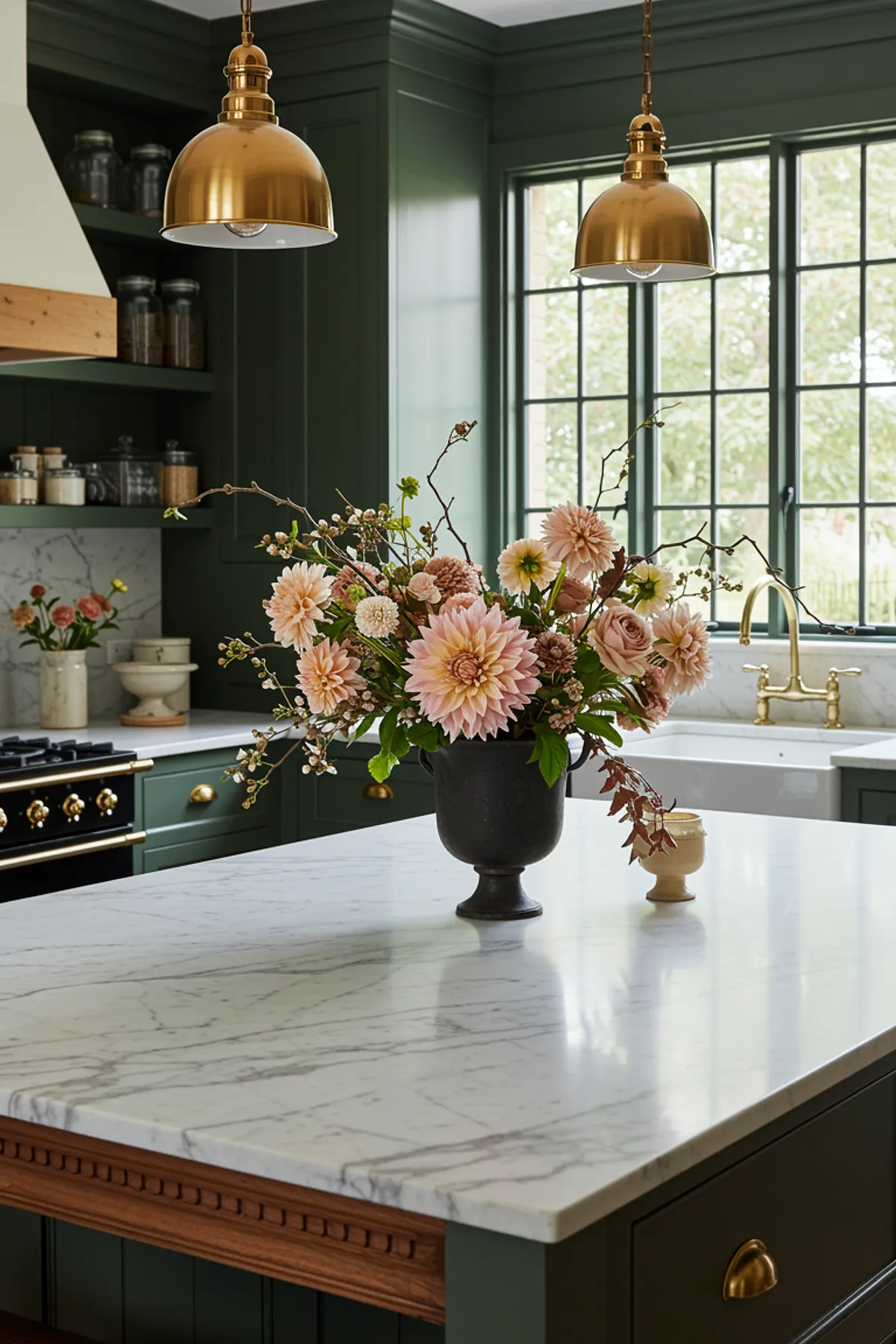 Modern farmhouse kitchen featuring green cabinets, marble island, and a floral arrangement.