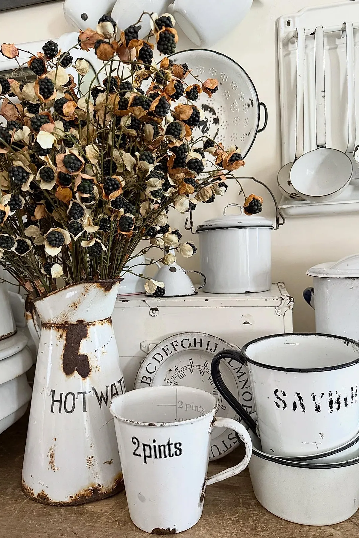 Vintage cottage kitchen display featuring rusty white enamelware including a pitcher with