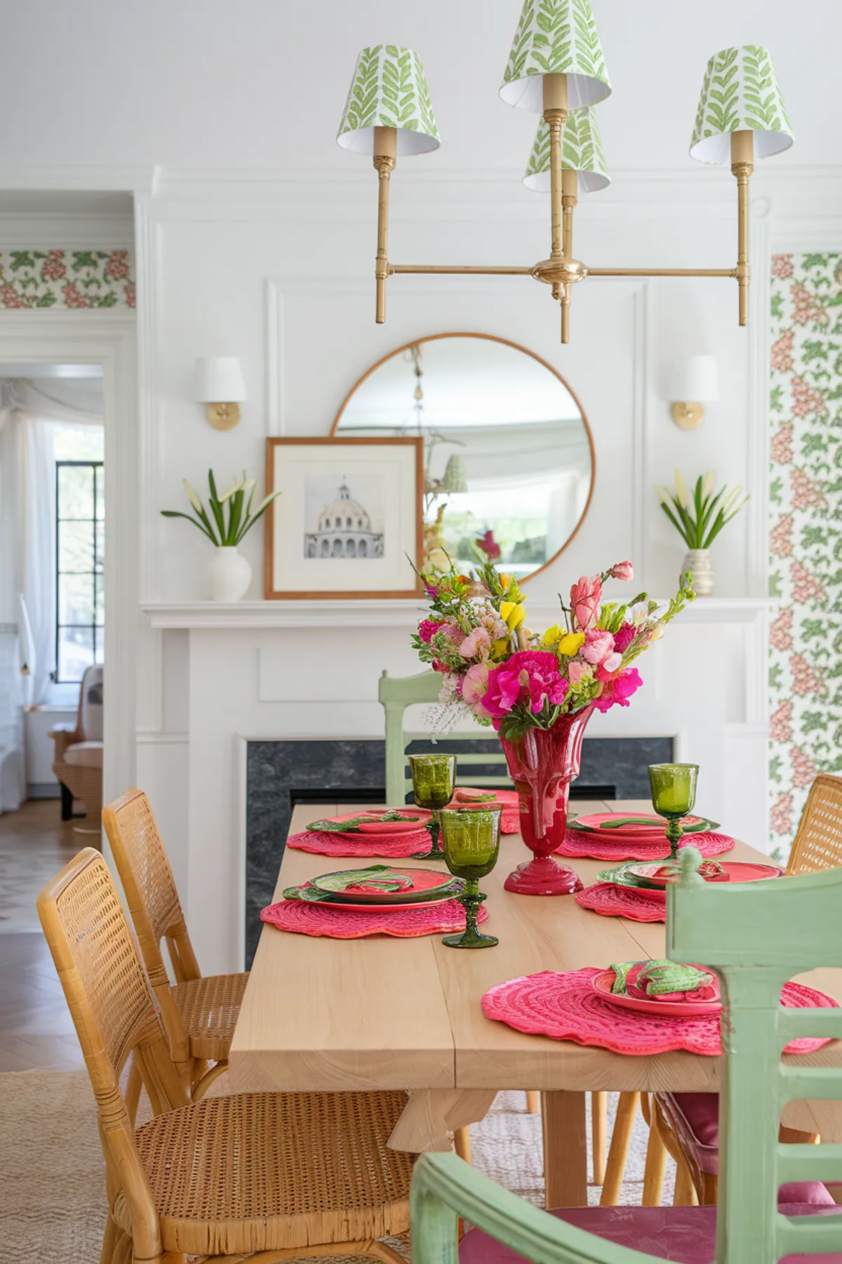 A colorful dining table with vibrant floral centerpiece, green glasses, and pink dishware.