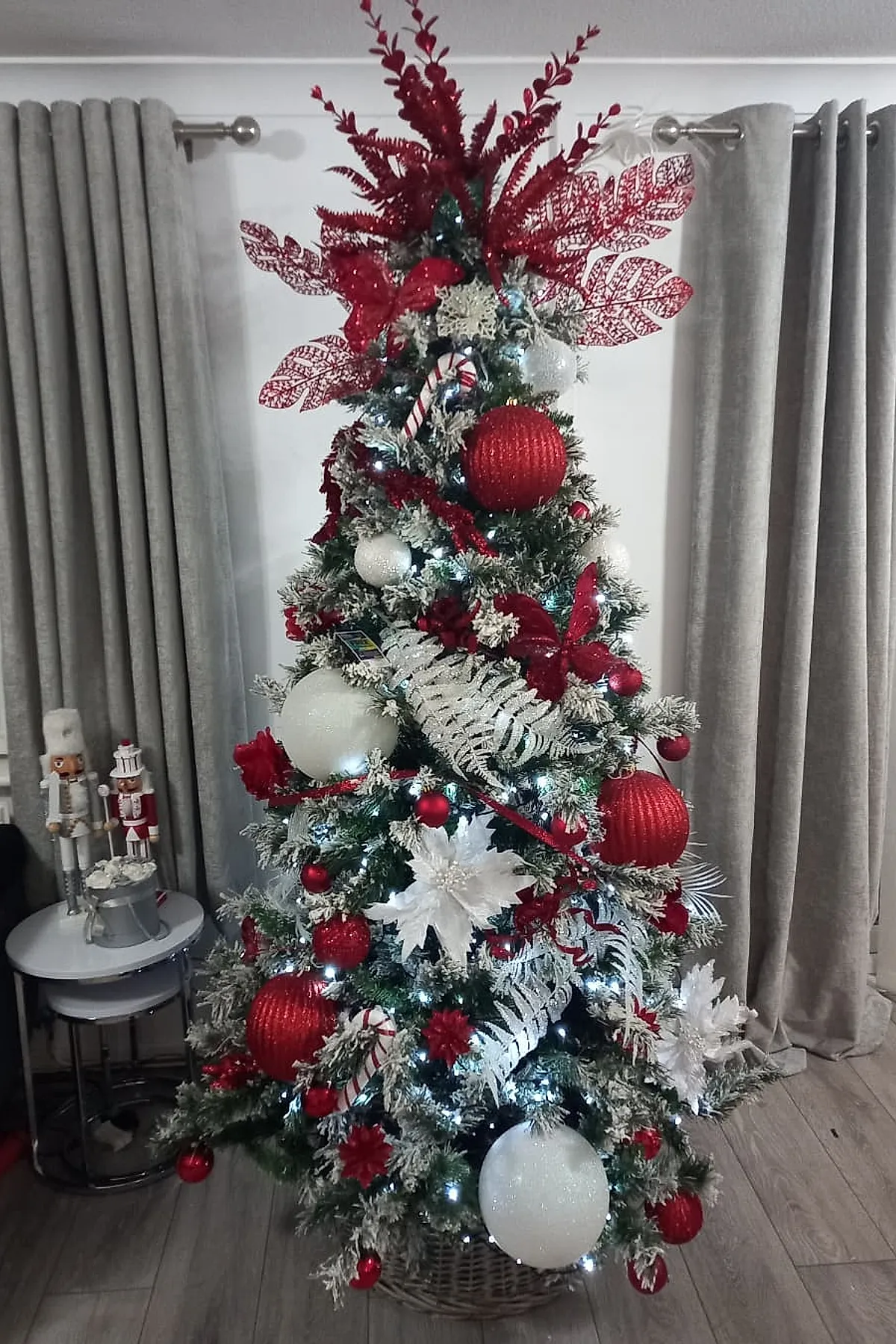 christmas tree ideas red and white featuring glittery red leaf sprays, oversized baubles, candy cane ornaments, and frosted greenery glowing under warm lights.