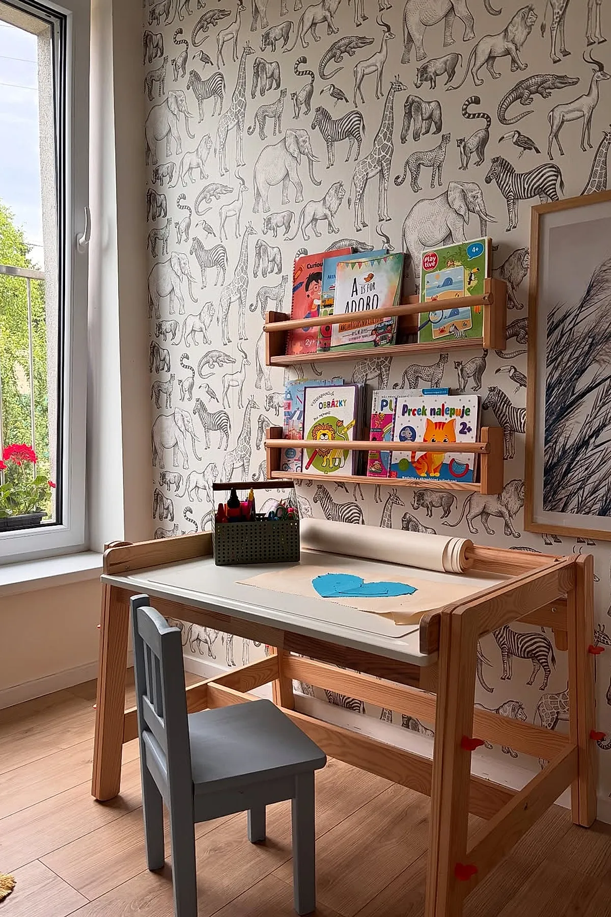 Kids room with desk featuring a wooden kids study desk with white tabletop, two wooden wall-mounted bookshelves filled with colorful children