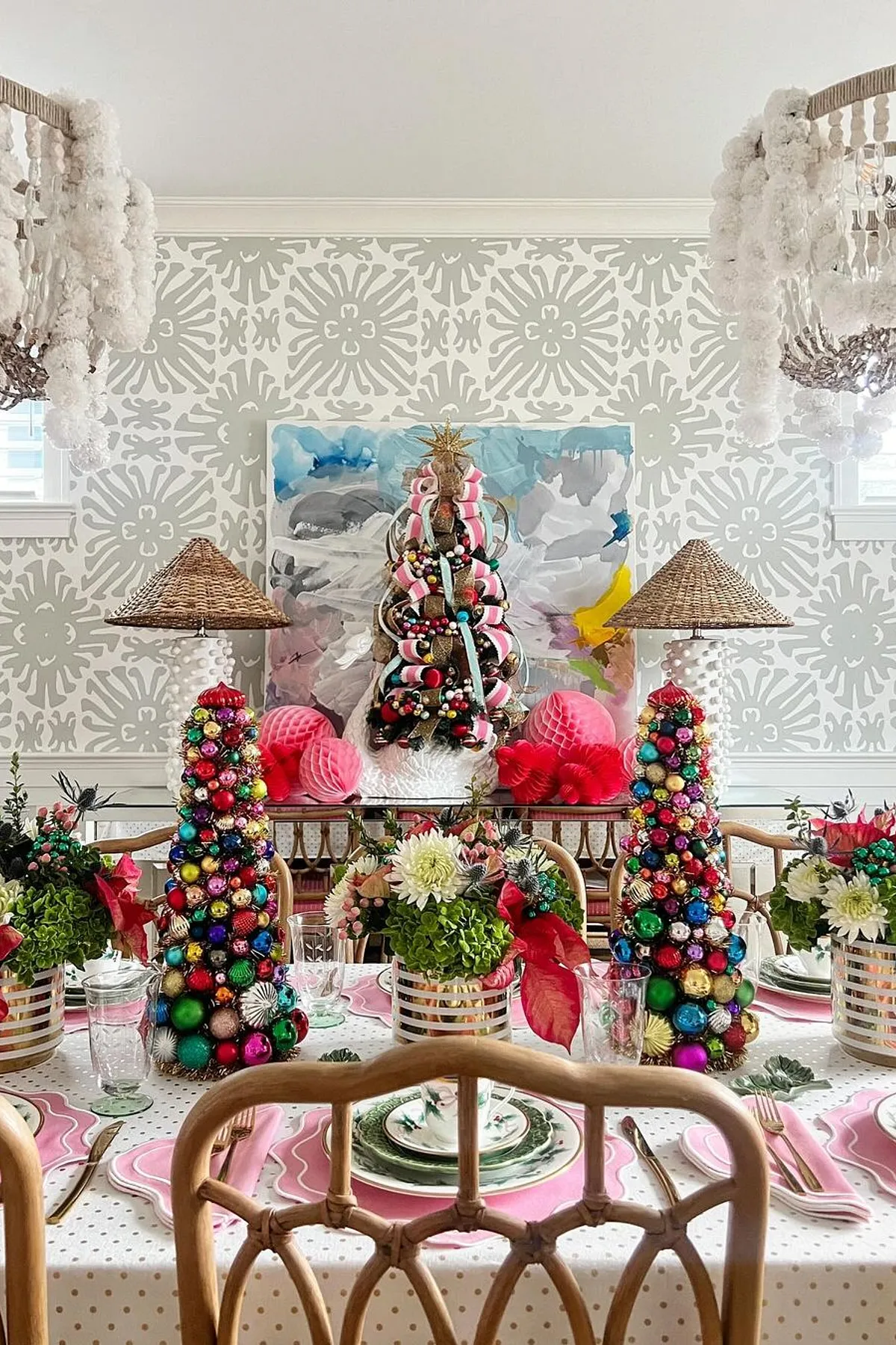 Elegantly decorated dining room with pink placemats, white china, colorful centerpieces, and chandeliers for a festive atmosphere.