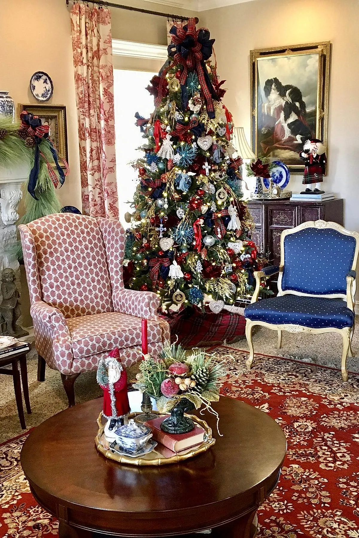 traditional christmas tree decorated with red and navy plaid ribbons tied in bows at the top, white crocheted angel ornaments, gold and red baubles, various shaped vintage-style ornaments, all illuminated by warm white string lights in a cozy living room.