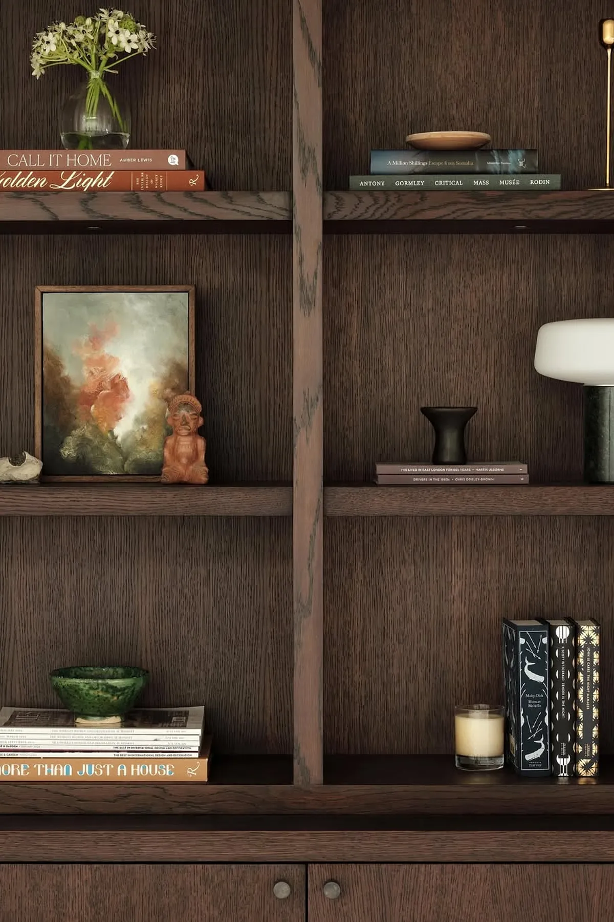 Modern shelf featuring dark wood background, decorative items, books, candle, and an artwork in a living room.